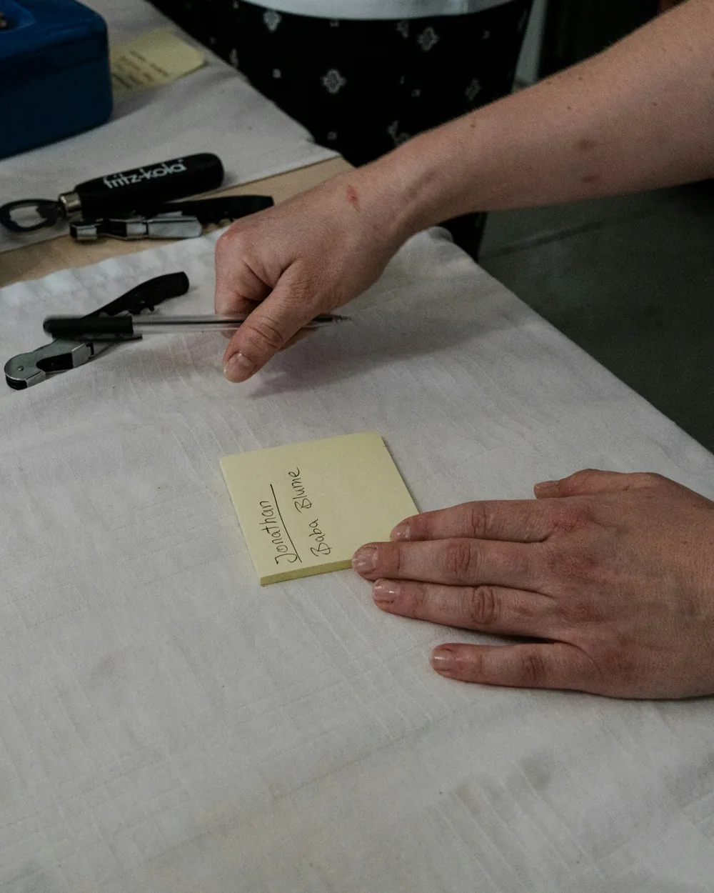 Ruce s nůžkami při ořezávání listu papíru na pracovním stole